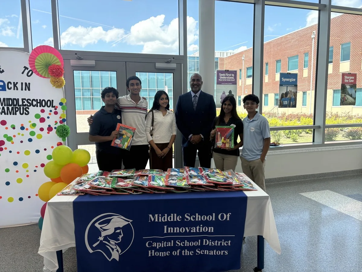 SkillSphere's student team with a Capital School District administrator at the Dover Middle School supply distribution table.